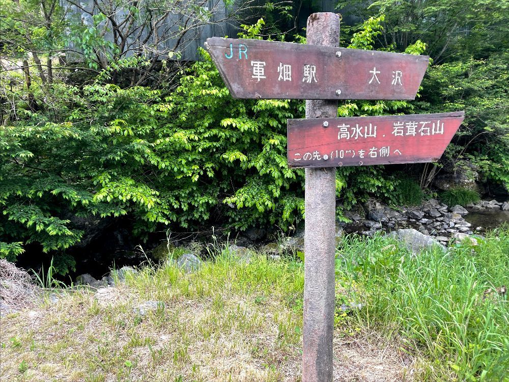 Signs on trail in Japan to JR station and mountains